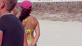 young girl struts a tiny bikini on the beach while boyfriend’s relatives watch.