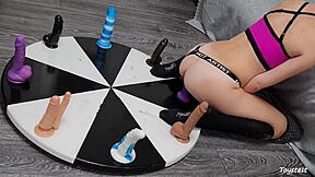 She desperately wants to win her orgasm on the wheel of dildos